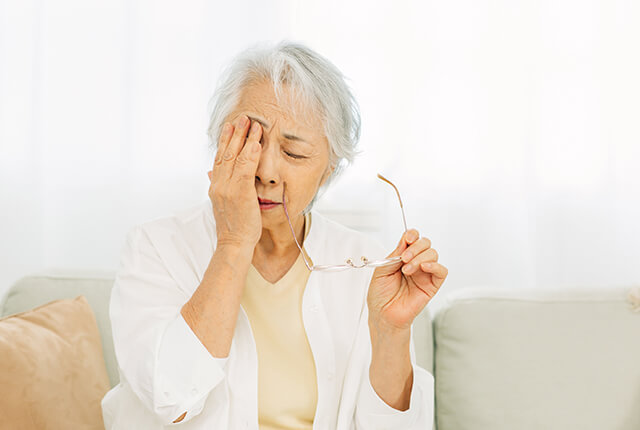 眼を押さえている高齢女性