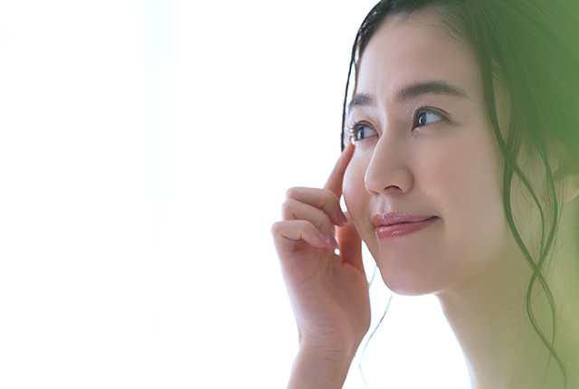 目元に指を添えて微笑む女性